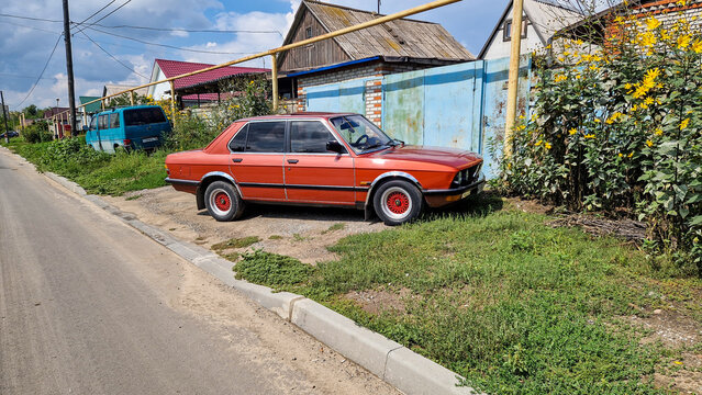 Classic red BMW 5 Series E28 vintage car parked by the roadside in front of houses in Rudny, a German automotive classic from the 1980s (produced 1981&ndash;1988), Kostanay, Kazakhstan 05.08.2025