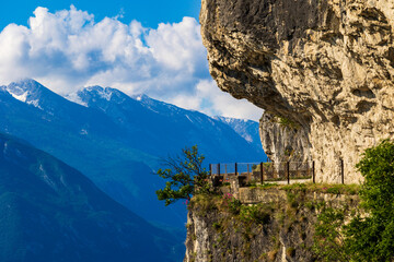 Naklejka premium Ponale trail carved into the cliff dropping directly into Lake Garda, offering a breathtaking view of the lake and the mountains of the opposite shore