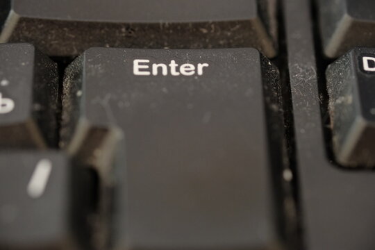 Close-up view of a dusty computer keyboard with a prominent Enter key, showcasing the texture and wear of the keys in a home or office setting