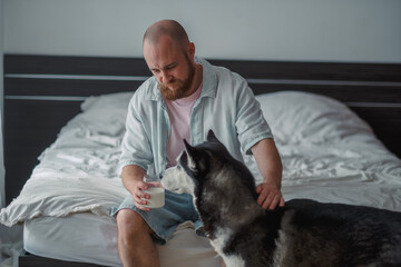Man and his husky sharing a morning on a bed at home © iwavephoto