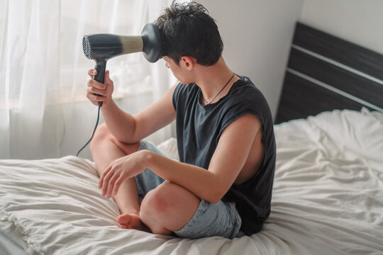 Teenage boy with a hairdryer with a diffuser nozzle