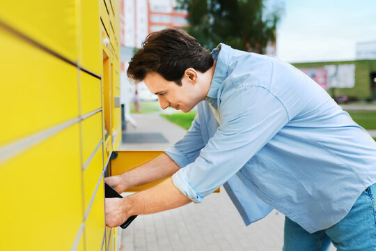 man picking up an online shopping package from a yellow parcel locker. A convenient contactless delivery service, ecommerce logistics, and self-service terminal.