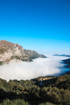 Espeso mar de nubes cubriendo un valle de monta&ntilde;a con picos rocosos emergiendo bajo el cielo