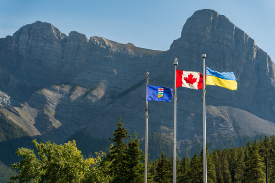 Provincial flag of Alberta, Canadian flag, and Ukrainian flag flying together in the Rockies. Canmore, Alberta, Canada.