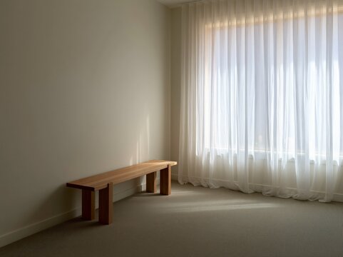A minimalist interior with a wooden bench placed against a neutral wall, bathed in soft light filtering through sheer curtains