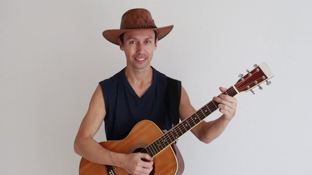 homem sertanejo usando chap&eacute;u de vaqueiro e tocando viol&atilde;o acustico 