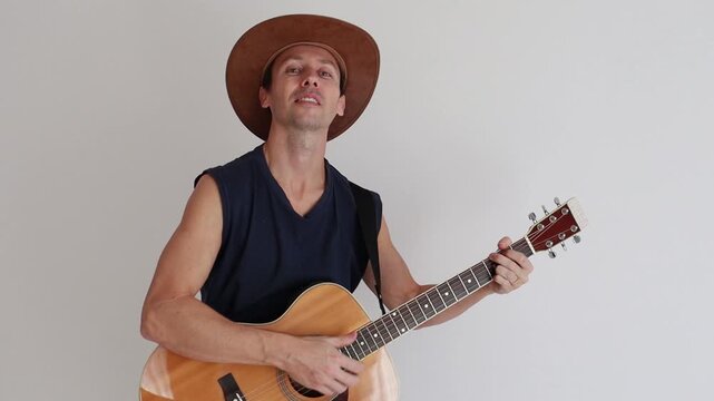 homem sertanejo usando chap&eacute;u de vaqueiro e tocando viol&atilde;o acustico 