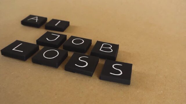 Black letter tiles spelling AI Job Loss on a cardboard background, representing unemployment and the future of work caused by automation, robotics, and technological advancements