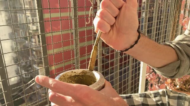 Preparing Traditional Yerba Mate. Infusion Warm Drink Lifestyle Scene on terrace, balcony, rooftop, Fall Day. Typical social drink from Latin America, Argentina, Uruguay, Paraguay and Brazil.