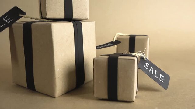 Stylish gift boxes wrapped in brown craft paper with black ribbons and sale tags, ideal for promoting special offers, discounts, and holiday shopping events like Black Friday or Cyber Monday
