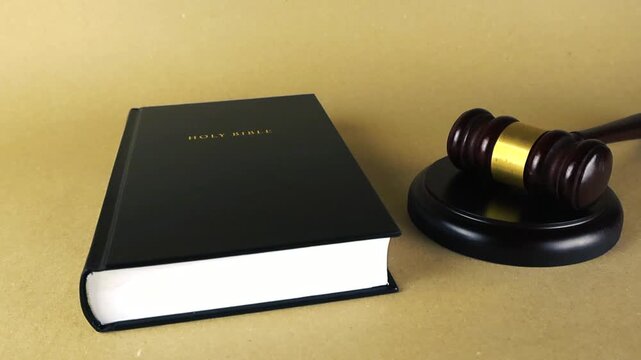 Holy Bible and a judge's gavel sitting on a wooden desk representing the concept of divine law, justice, truth, and morality in the courtroom, court of law or judicial system of government