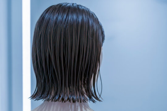 Woman getting dark hair wet in a salon