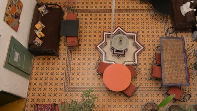 Marrakech, morocco. August 8, 2026. Top down view of a traditional moroccan riad courtyard. Ornate tilework, a central fountain, and lush plants creating a serene oasis