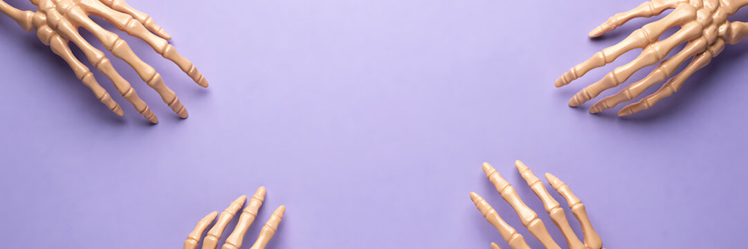 Four plastic human skeleton hands arranged in the corners of a light purple background, for medical anatomy, biology study, or, halloween themes