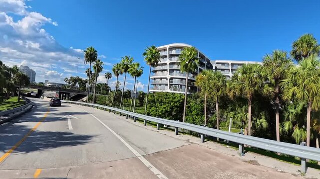  Modern Miami roadway combines traffic, tropical greenery, and distinctive waterfront architecture.

