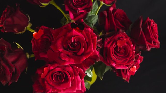 Stunning bouquet of vibrant red roses with small decorative hearts on the petals against a dark background, slowly moving in a romantic and elegant display perfect for a special occasion