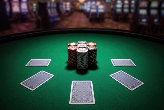 Poker chips stacks and playing cards on green casino table background