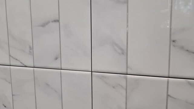 White ceramic wall tiles with marble pattern texture installed indoors, bathroom renovation, interior design, home improvement.
