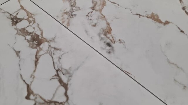 White ceramic floor tiles with marble pattern texture installed indoors, home renovation, interior design, flooring materials.