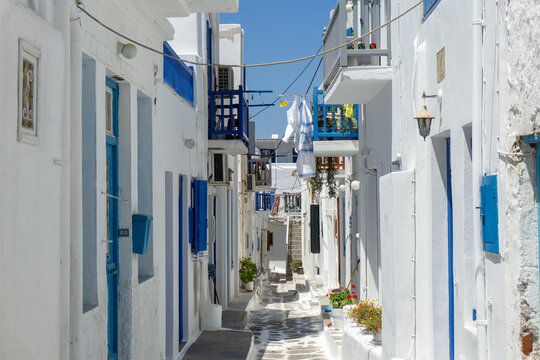 Mykonos town alley with traditional white houses and blue details