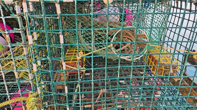 New England style lobster trap stack with blue wire cages, green mesh, ropes, and red buoy, creating a detailed maritime background for working harbor footage.