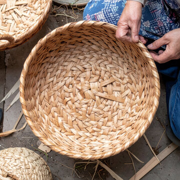 Hands weaving natural rattan basket traditional craft closeup top view