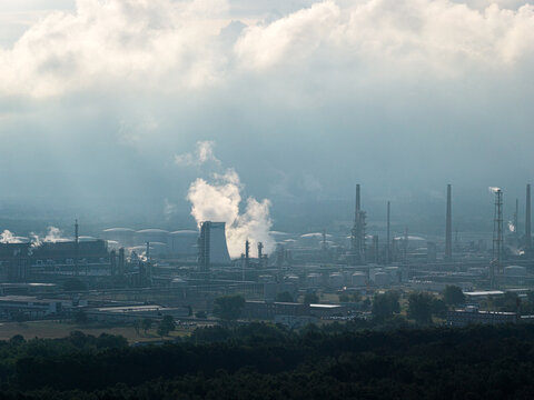 SchwedtOder, Brandenburg, Germany - 20 August 2026: Aerial view of PCK Raffinerie GmbH with industrial smoke stacks, storage tanks, and complex infrastructure amidst forest under a cloudy sky.