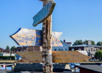 Weathered handmade wooden direction arrows on birch signpost. © Trygve