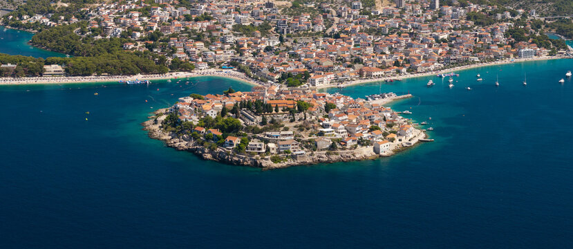 Aerial panoramic view of Primo&scaron;ten, Croatia, showing the historic peninsula, red rooftops, turquoise Adriatic waters, beaches, marina, surrounding islands and rugged Mediterranean coastline.