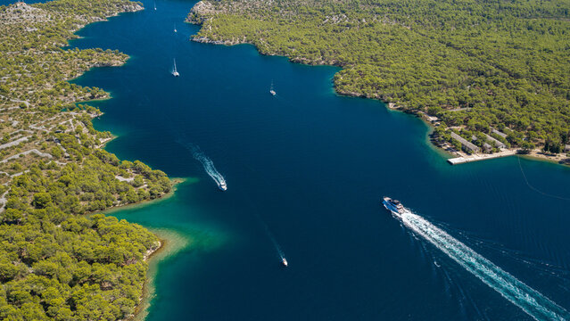Aerial view of Luka Channel near &Scaron;ibenik, Croatia, featuring rugged pine-covered islands, deep blue Adriatic waters, rocky coastline and boats creating dynamic wakes across the channel.