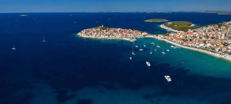 Aerial panoramic view of Primo&scaron;ten, Croatia, showing the historic coastal town, red rooftops, turquoise Adriatic waters, yachts, sandy beaches, Mediterranean architecture and sunny summer scenery.