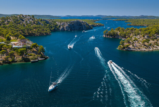 Aerial view of Luka Channel near &Scaron;ibenik, Croatia, featuring rugged pine-covered islands, deep blue Adriatic waters, rocky coastline and boats creating dynamic wakes across the channel.