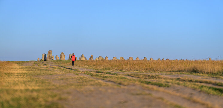 Ystad, Sweden - August 02 2026: Visitor approaching panoramic Ales Stones monument across grassland.