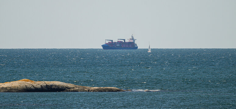 Gothenburg, Sweden - August 11 2026: Cargo ship and sailboat crossing open Swedish coastal waters.