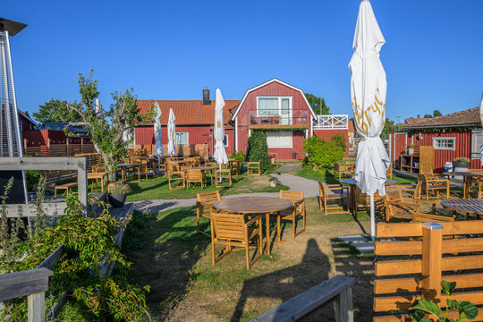 Sunny outdoor restaurant garden with wooden tables and umbrellas.