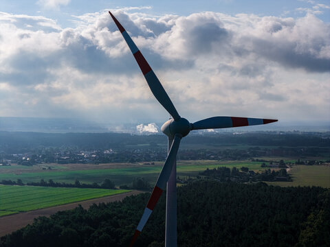 Schwedt Oder, Brandenburg, Germany - 20 August 2026: Aerial view of a wind turbine standing in a rural landscape with the PCK Raffinerie GmbH visible in the distance under a cloudy sky.