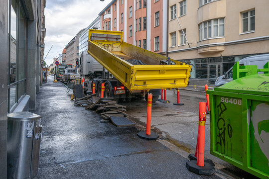 Helsinki, Finland - August 06 2025: Yellow dump truck unloading materials at construction site.