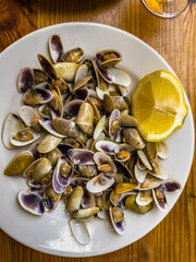Steamed clams with lemon slice on white plate © Ernesto Sevilla