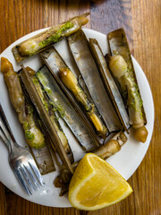Razor clams on plate with lemon wedge © Ernesto Sevilla