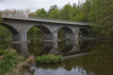 Fototapeta premium Moderne Straßenbrücke über die Saale mit Metallgeländer, Uferstraße im Sommer, Wald im Hintergrund, Verkehrsinfrastruktur, Ziegenrück, Saale-Orla-Kreis, Thüringen, Deutschland