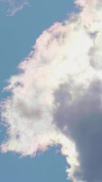Vertical video of dramatic backlit clouds on blue sky with bright sunbeams and silver lining effect