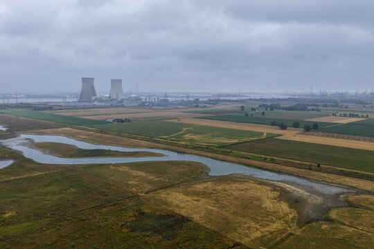 Beveren-Kruibeke-Zwijndrecht, Belgium - 18 August 2026: Aerial view of the Doel Nuclear Power Plant surrounded by agricultural fields and the Scheldt river under a cloudy sky.