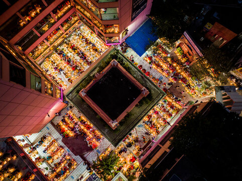 Dhaka, Bangladesh - 04 November 2023: Aerial view of Swamibagh Road illuminated by lamps during a festive night, with people gathered in the courtyard of a building complex.