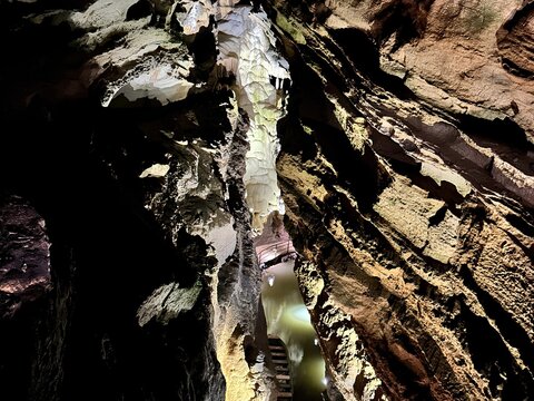 Illuminated underground cave passage with a subterranean lake, stairs, and massive limestone rock formations