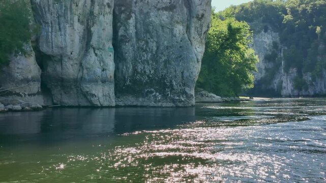 Scenic journey along the sparkling Danube River, passing by majestic limestone cliffs and lush green forests in the beautiful region of Bavaria