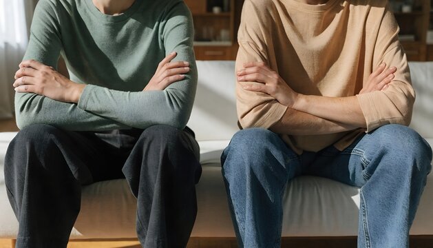 Two adults sitting with crossed arms indoors, showing tension and disagreement in a serious relationship moment