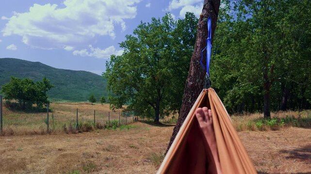 First person hammock swing overlooking green mountains
First person view of legs gently swinging in a hammock with lush trees and green mountain scenery beyond. Peaceful nature escape, relaxation 