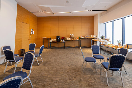 Modern conference hall featuring a coffee break station and buffet setup with blue chairs