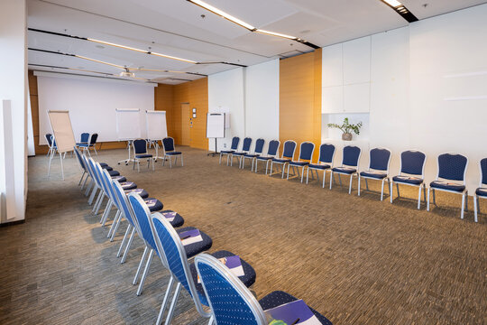 Modern conference room layout with blue chairs placed in a semi circle facing flip charts