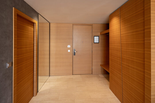 Modern hotel room entrance hallway with elegant wooden wall paneling and mirror